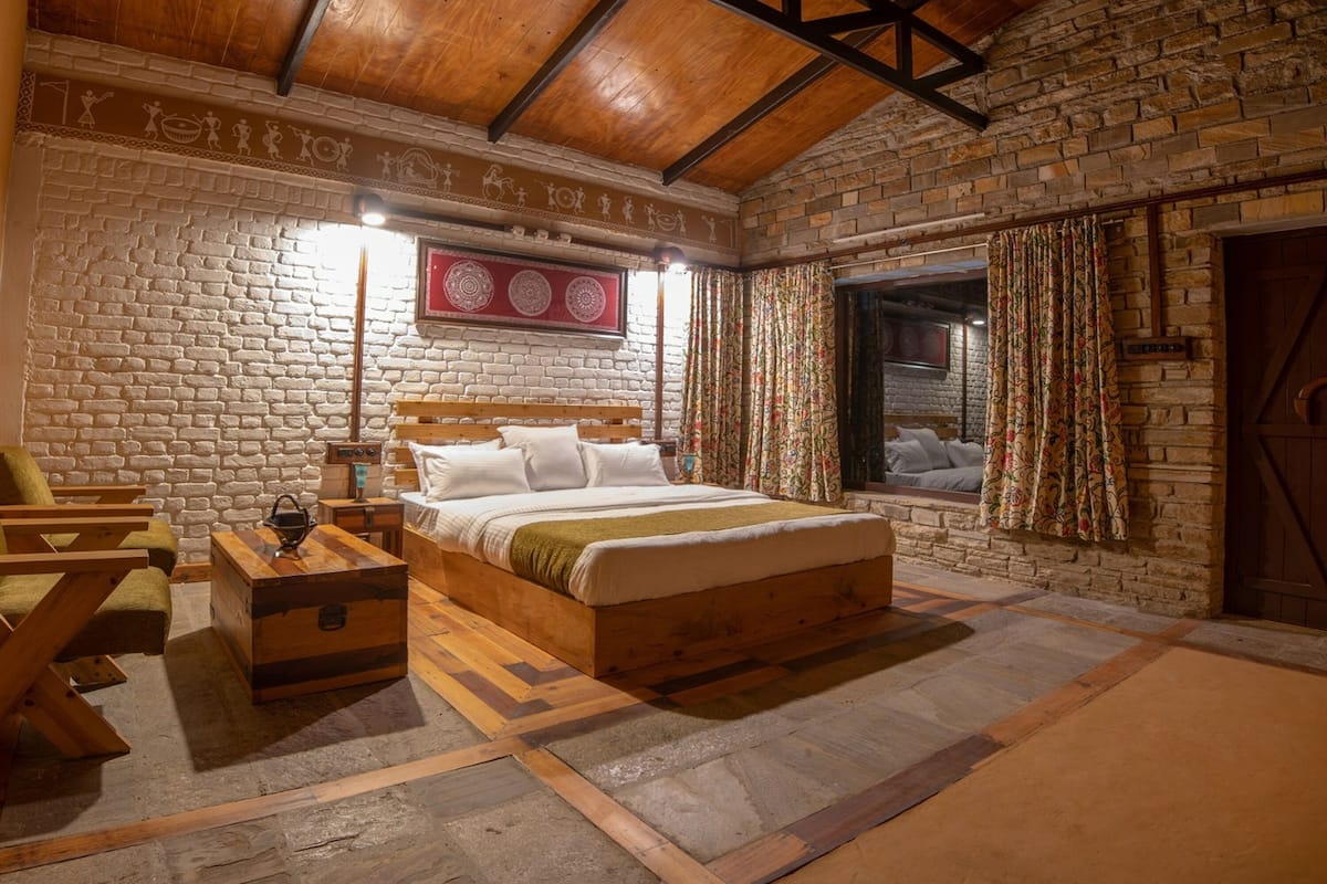Een eenvoudige slaapkamer met een houten bed, een dressoir en een stenen muur.