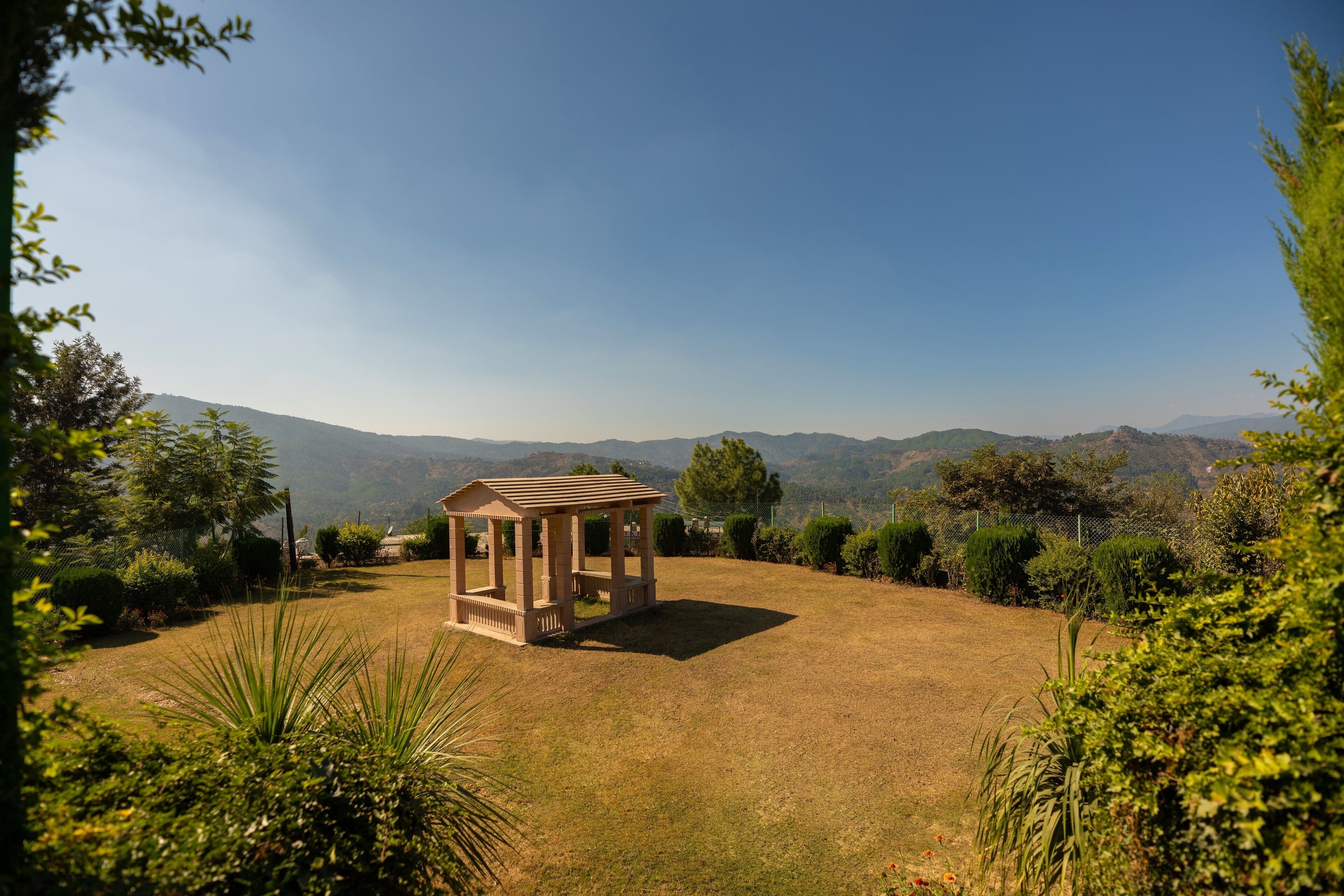 A gazebo in a grassy area with a view of distant mountains.
