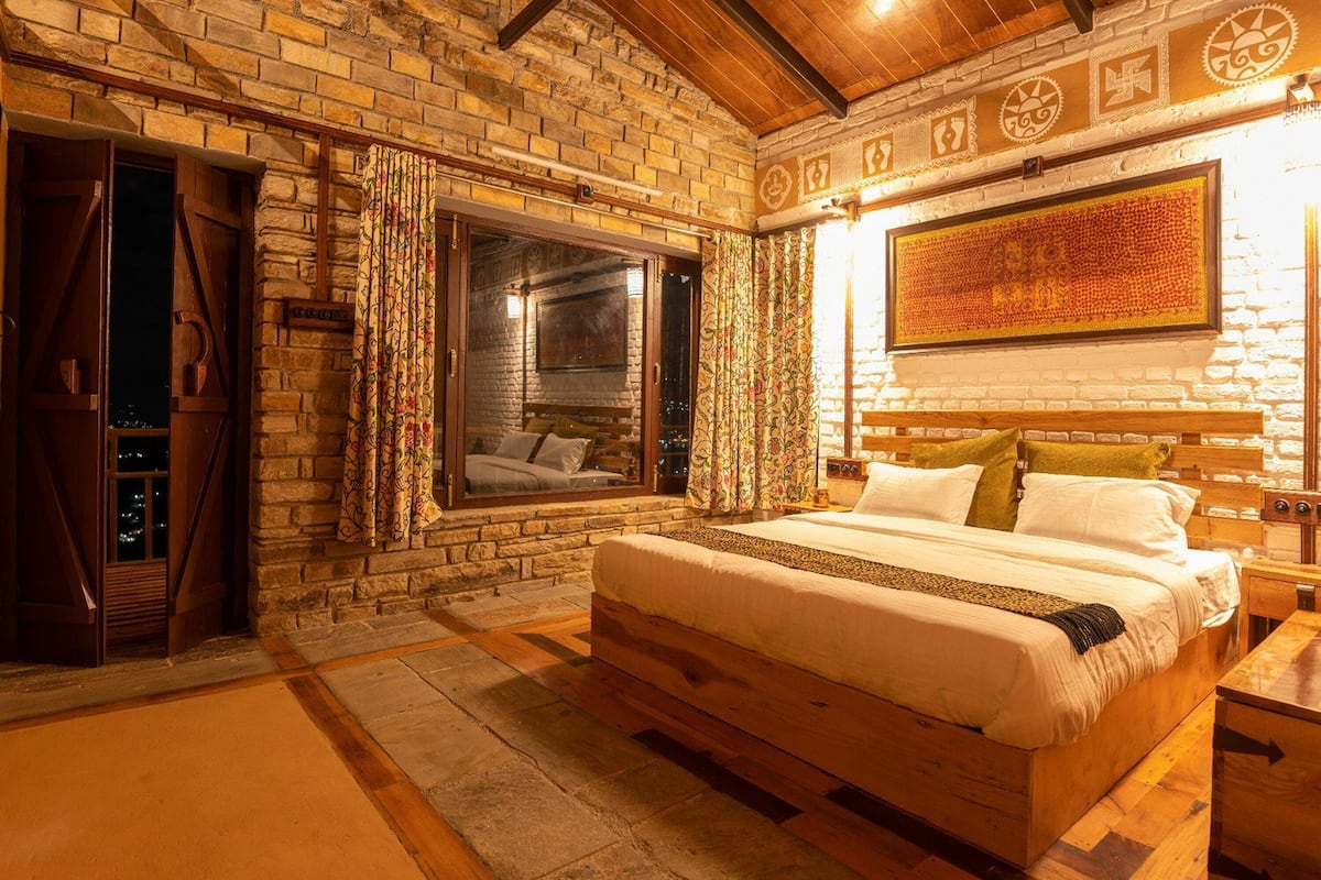 Een gezellige slaapkamer met een stenen muur, een groot bed, een raam en een nachtkastje.