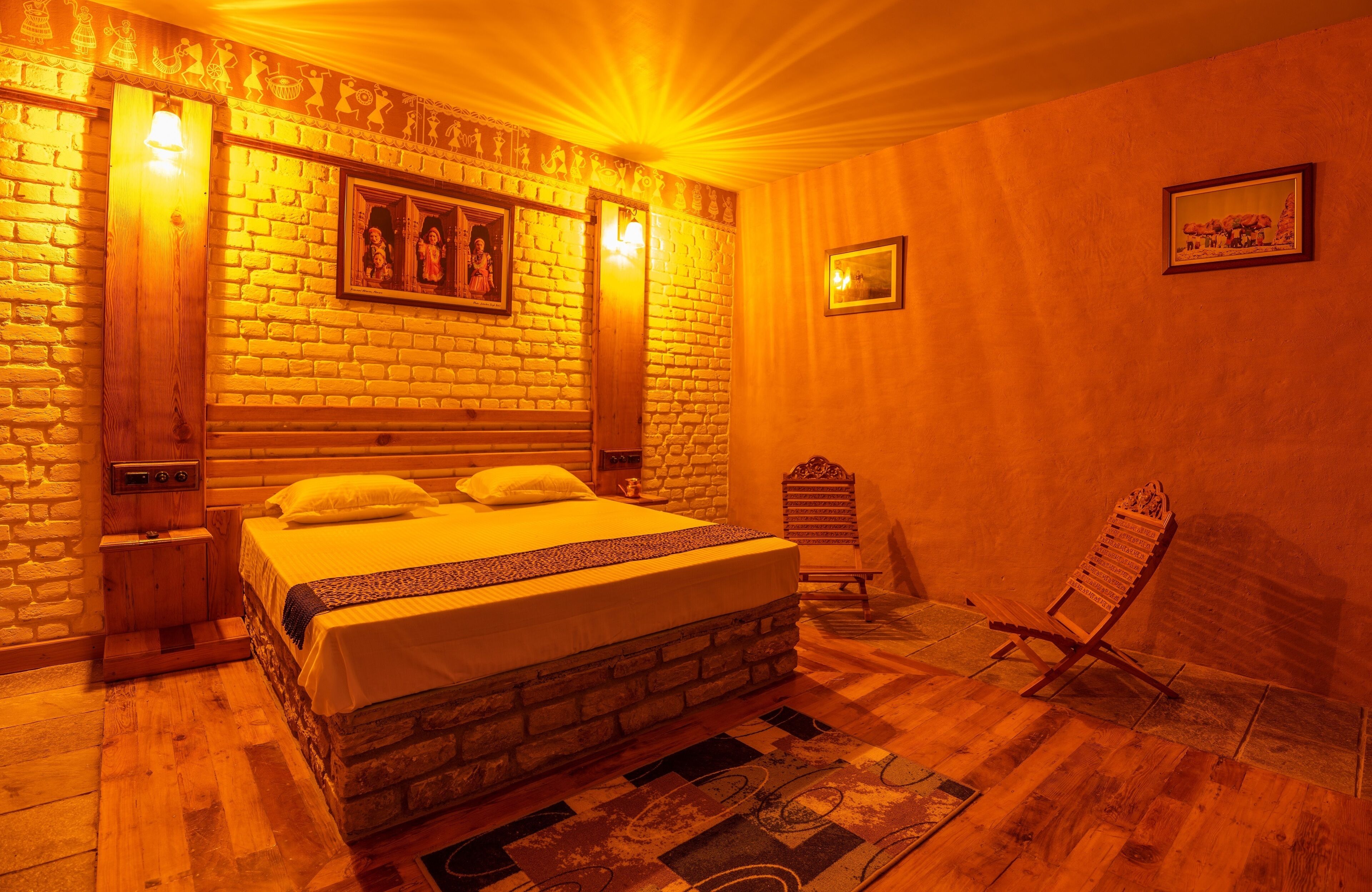 A room with a brick wall, a wooden bed, a nightstand, a chair, and a framed picture on the wall.