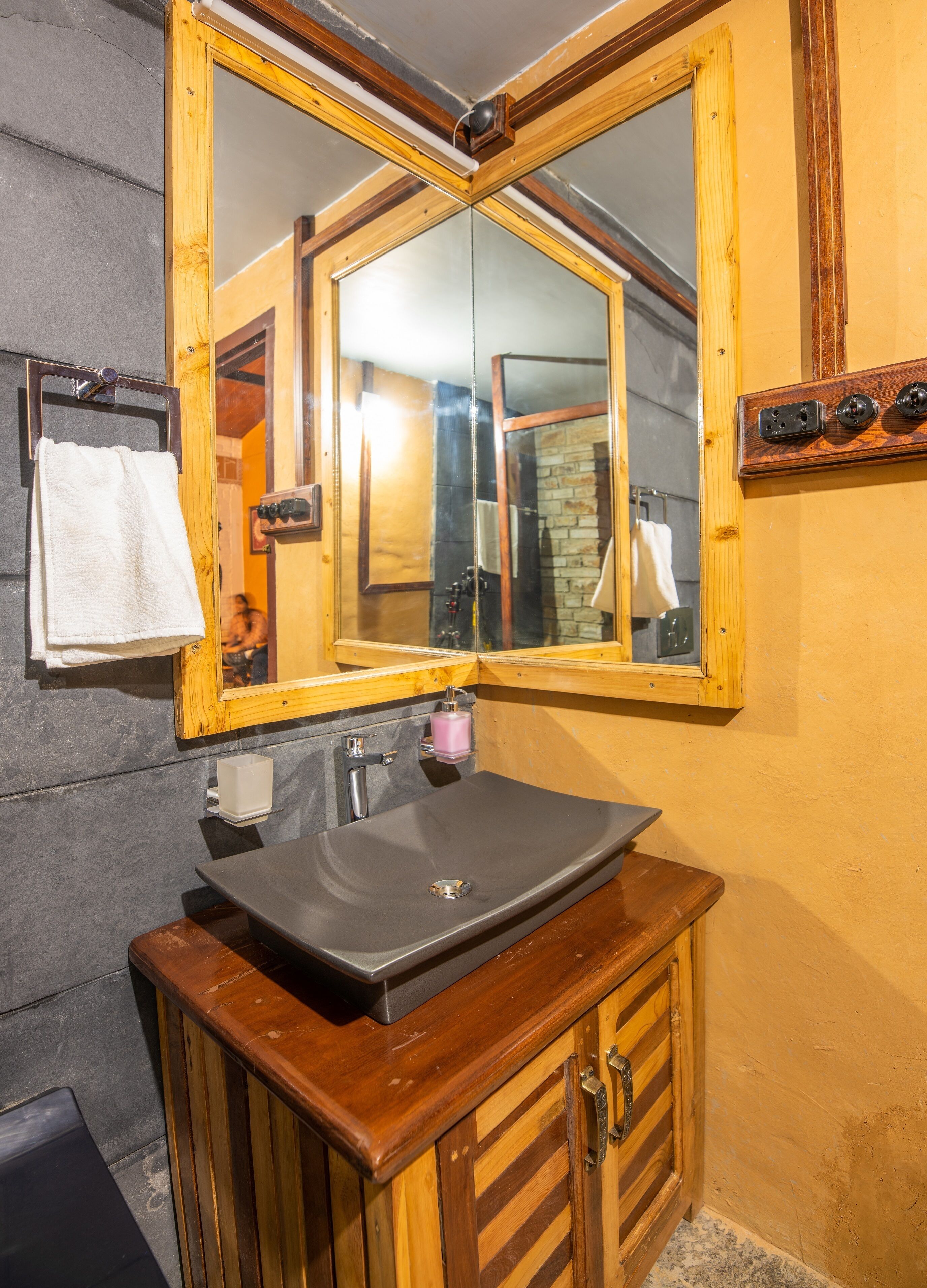 A bathroom with a wooden vanity, a large mirror, and a black sink.