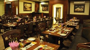 Un comedor formal con varias mesas dispuestas para comer, sillas de madera y un sofá.