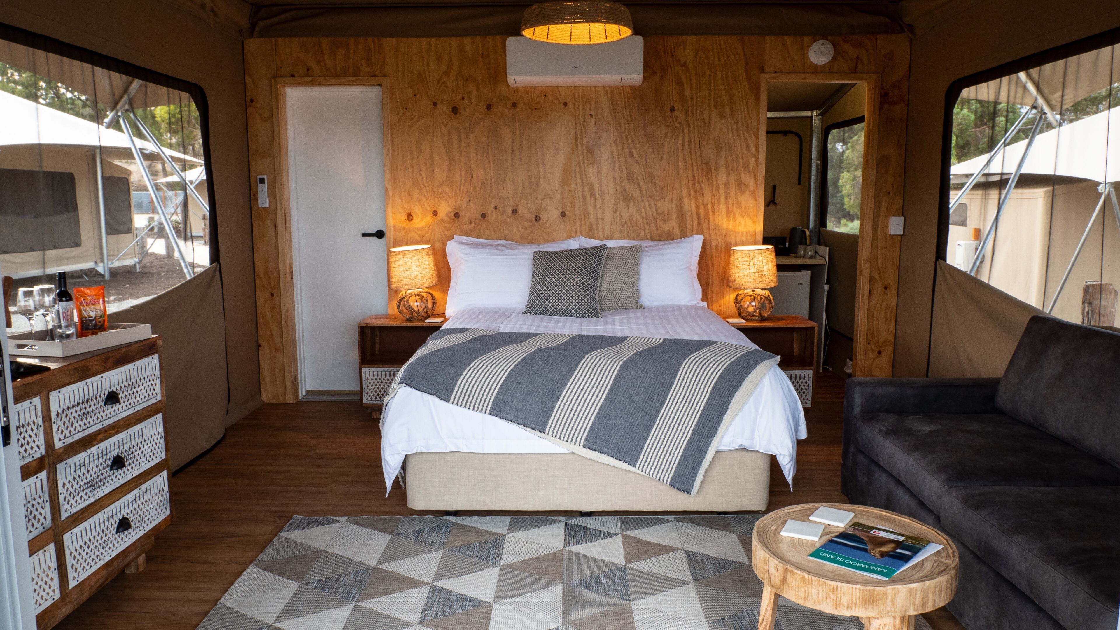 Un dormitorio acogedor con cama, lámparas de noche, un aparador de madera y un sofá.