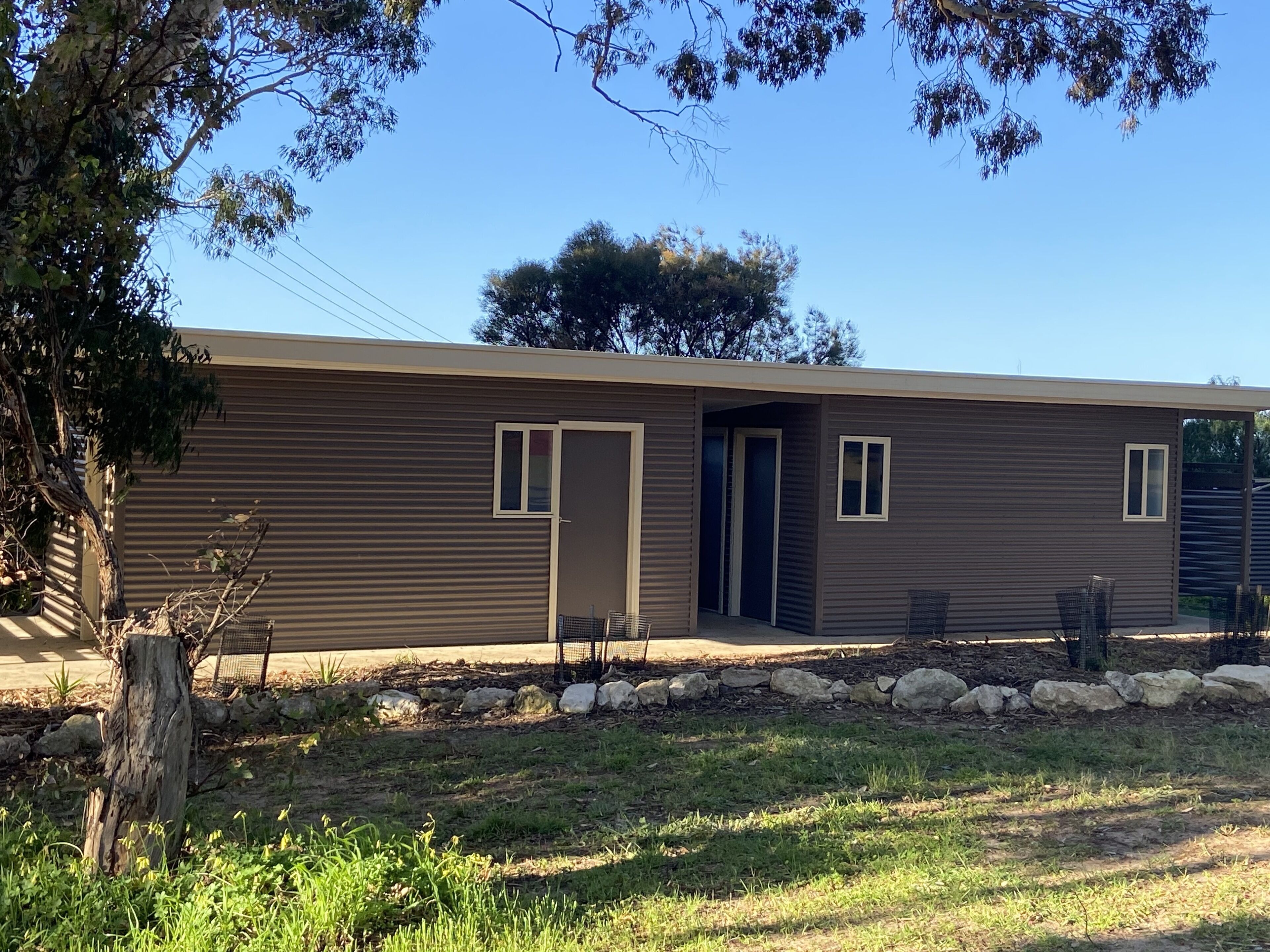 A modern single-story building with a flat roof, two small windows, and a door.