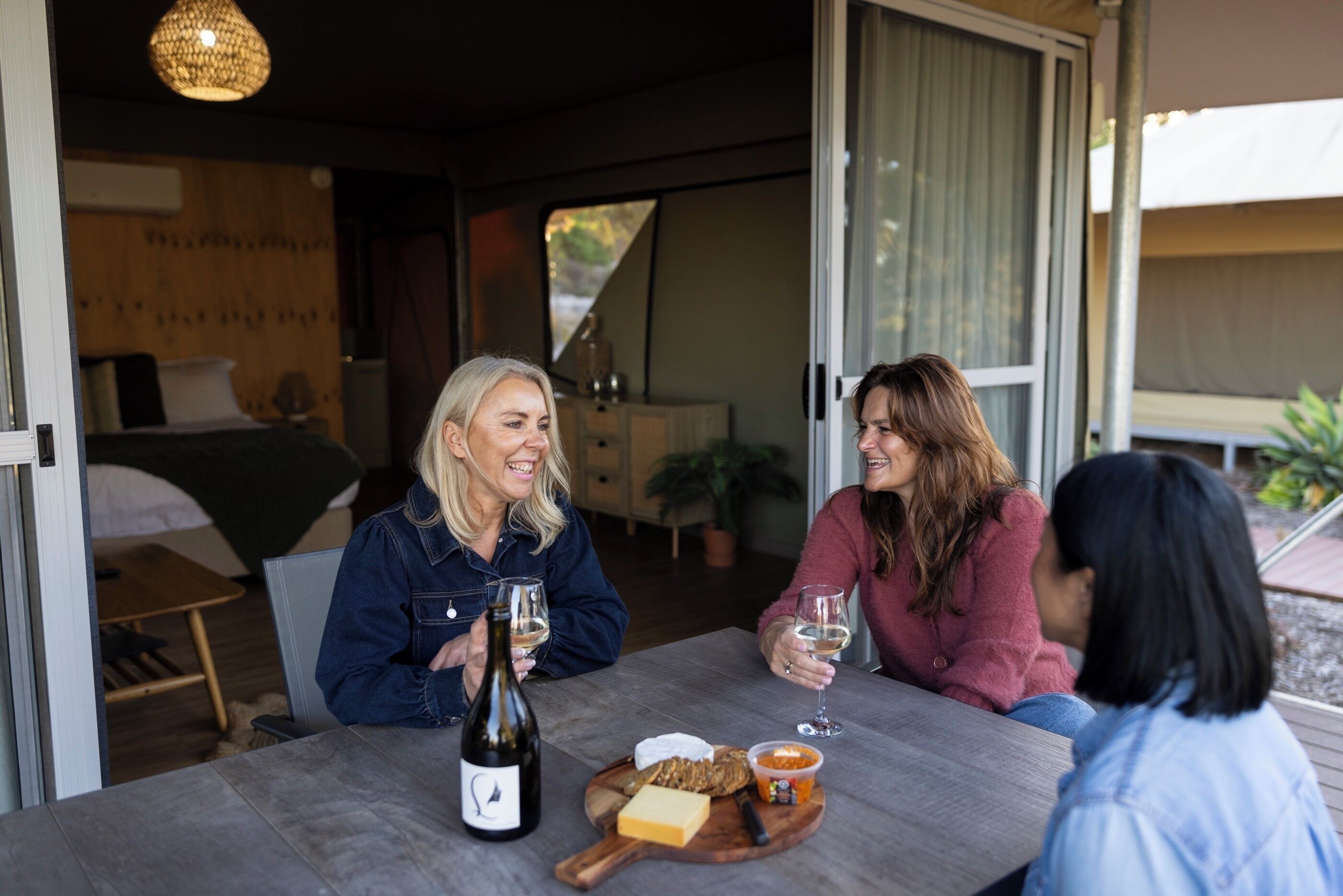 A dining table with a bottle of wine, cheese, and snacks.