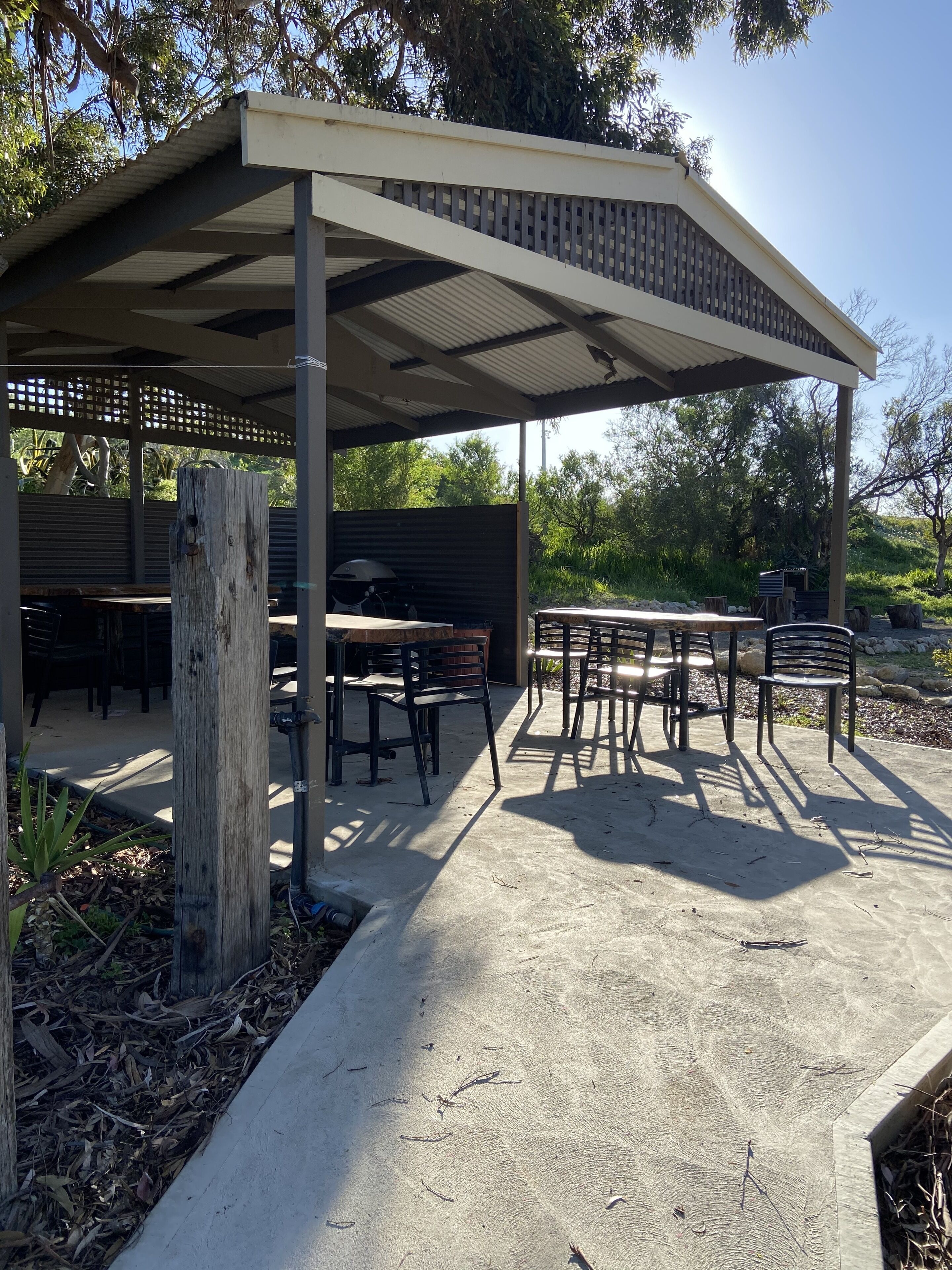 An outdoor patio area with a covered seating area, tables, and chairs.