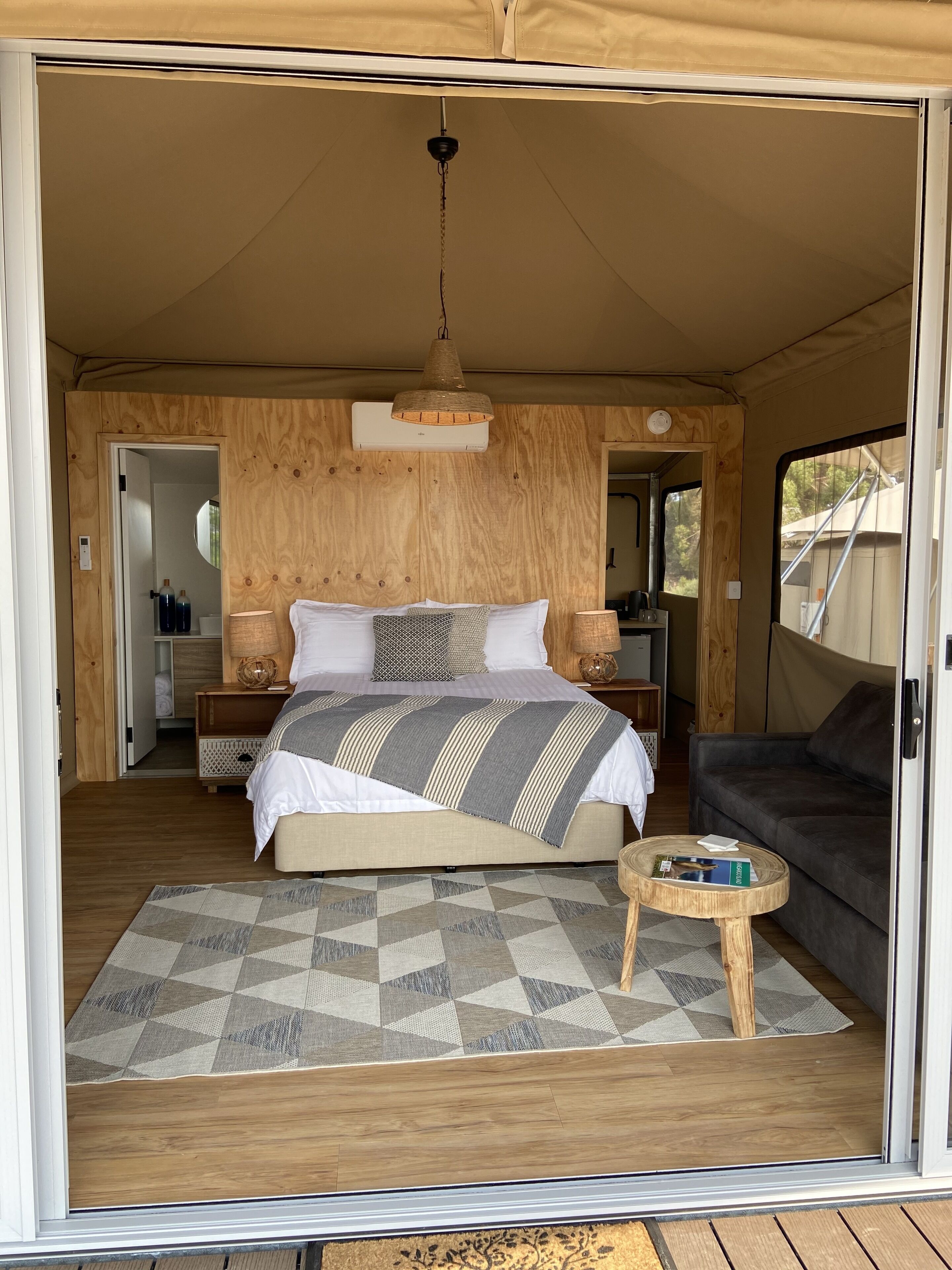 A cozy bedroom with a bed, bedside tables, a small round table, and a sofa.