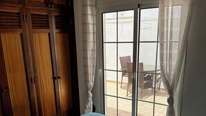 Et soveværelse med en stor seng, garderobeskab i træ og en skydedør til en udendørs terrasse.