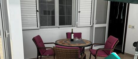 A patio area with a round table, four chairs, and a green umbrella.