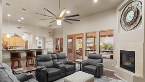 A spacious living room with a fireplace, ceiling fan, and dining area with bar stools. - Sprawling Arizona Oasis w/ Dream Backyard (New River)