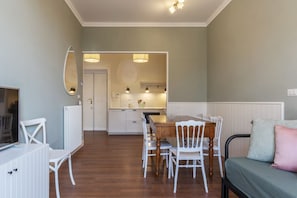 A room with a dining table, chairs, a TV, and a bed.