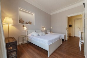 A bedroom with two beds, a bedside lamp, a mirror, and a small table.