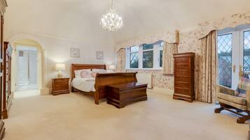 A bedroom with a large bed, a dresser, a nightstand, and a chair by the window.