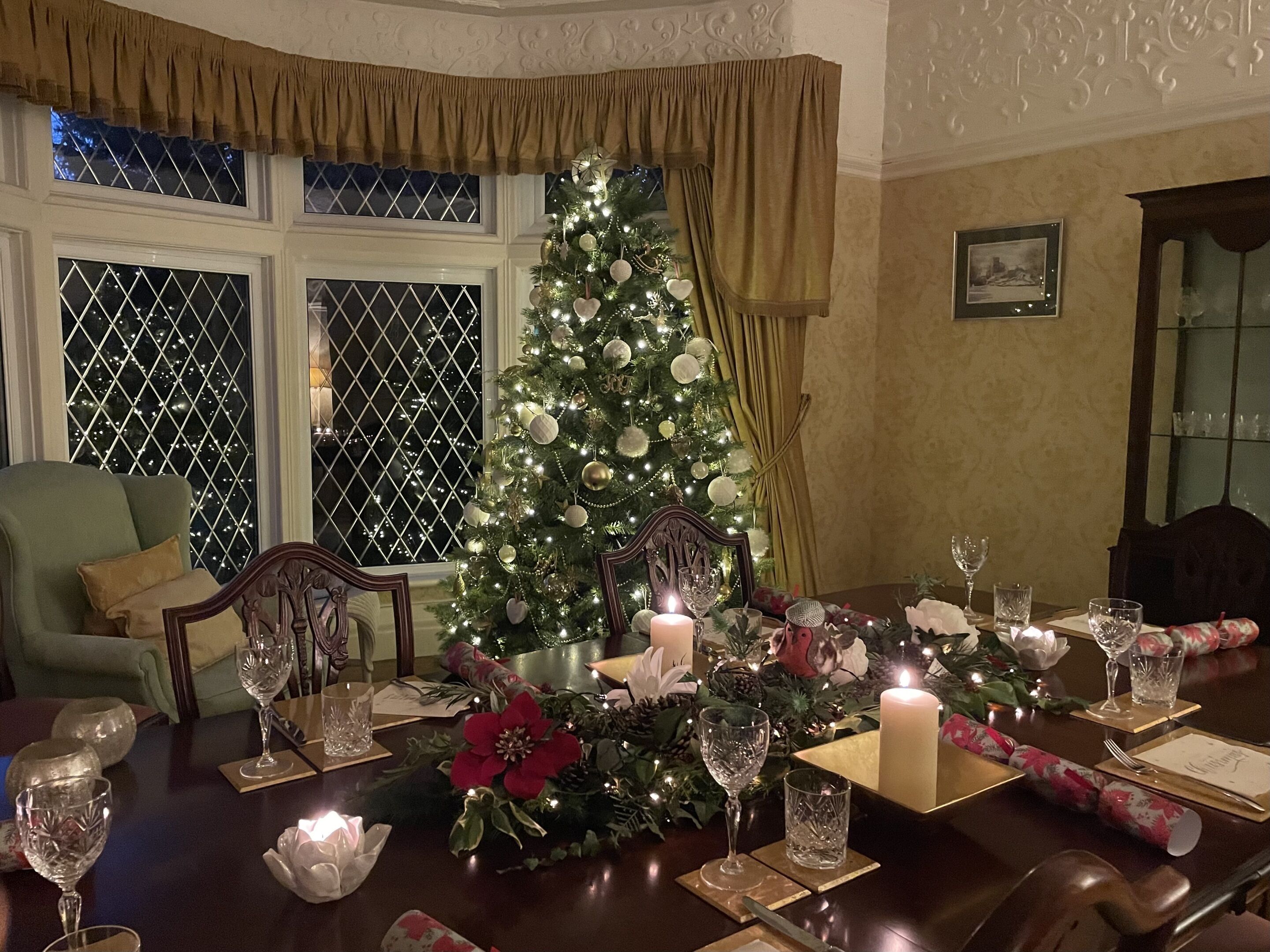 A dining room with a Christmas tree, a large candle, and a table set for a meal.