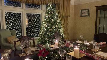 A dining room with a Christmas tree, a large candle, and a table set for a meal.