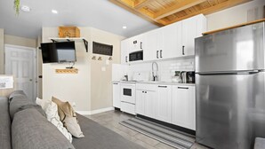 A modern kitchen with white cabinets, a stainless steel refrigerator, and a built-in microwave. - Chouette Tremblant Ski In/Out Pedestrian Village (Mont-Tremblant)