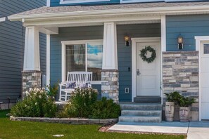 A house with a porch, a front door, and a stone accent wall.