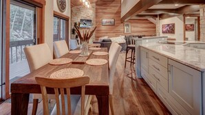 Un comedor amplio con una larga mesa de madera, sillas acolchadas y una pared de acento de piedra.