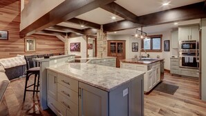 Una cocina amplia con una isla grande, vigas de madera y electrodomésticos modernos.