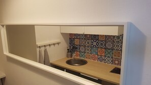 Cocina compacta con encimera de madera, pileta de acero inoxidable y salpicadero con baldosas de colores.