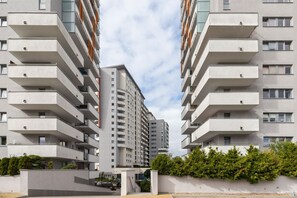 A modern apartment building with multiple balconies and a central entrance.