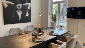 Un comedor moderno con una mesa larga, varias sillas y un cuadro abstracto grande en la pared.