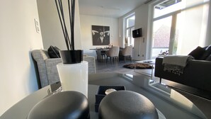 Una sala de estar moderna con un sofá, una mesa de centro y un comedor al fondo.