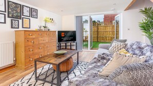 A living room with a wooden cabinet, a TV, a sofa, and a patterned rug. -  ByEvo Oswestry Barn - Quirky 2 Bed 1 Bath Barn style annex close to town centre (Oswestry)