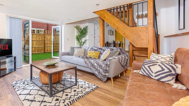 A modern living room with a grey sofa, wooden coffee table, and a staircase with a wooden railing. -  ByEvo Oswestry Barn - Quirky 2 Bed 1 Bath Barn style annex close to town centre (Oswestry)