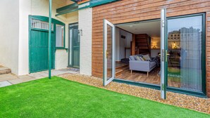 A modern house with a green door, a sliding glass door leading to a living area with a sofa and a lamp. -  ByEvo Oswestry Barn - Quirky 2 Bed 1 Bath Barn style annex close to town centre (Oswestry)