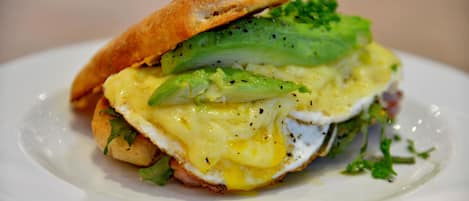 A sandwich with egg and avocado on a white plate.