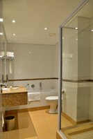 A modern bathroom with a glass-enclosed shower, a bathtub, and a toilet.