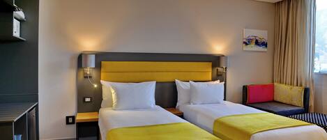 Habitación de hotel con dos camas, un sofá, un televisor y un cuadro en la pared.