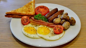A plate of breakfast food including eggs, sausages, bacon, mushrooms, tomatoes, and toast.