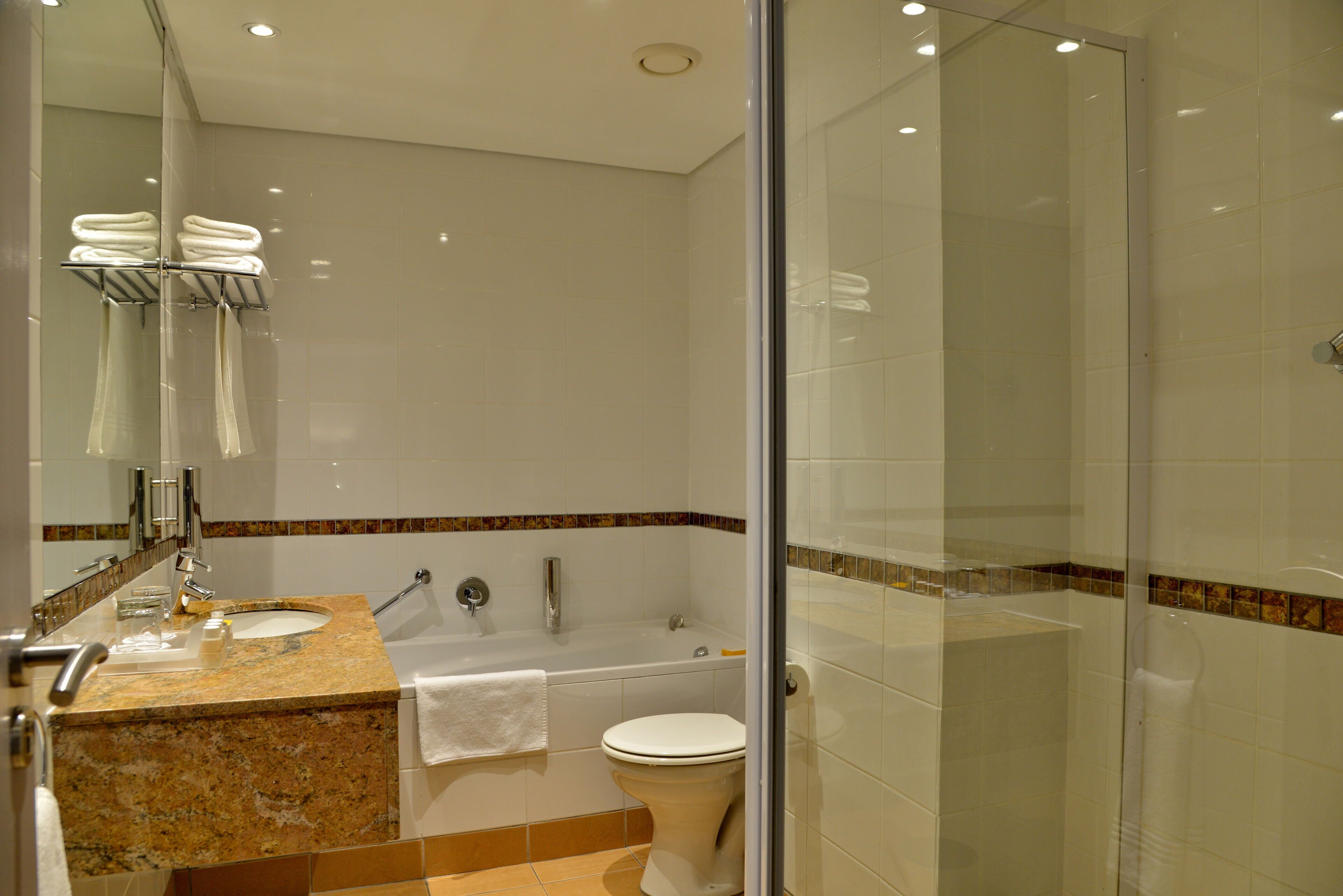 A modern bathroom with a glass shower enclosure, a double sink vanity, and a toilet.