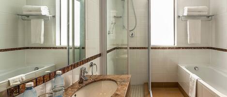A modern bathroom with a glass-enclosed shower, a bathtub, and a sink with a marble countertop.