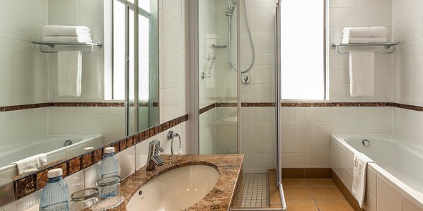 A modern bathroom with a glass-enclosed shower, a bathtub, and a sink with a marble countertop. - Cresta Grande Cape Town (Cape Town)