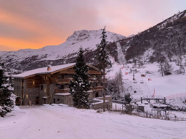 Una cabana plena de neu amb un telefèric al fons.