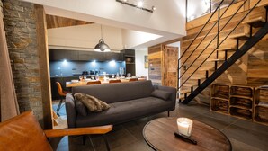 Een moderne woonkamer met een bank, een salontafel en een eethoek op de achtergrond.