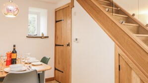 Comedor con una mesa de madera dispuesta para dos personas, una lámpara colgante y una escalera de madera.