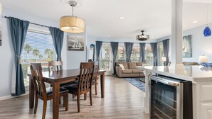 A modern kitchen with a built-in oven, wooden dining table, and blue curtains.