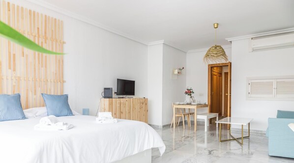 Una habitación de hotel con cama, escritorio, silla, televisor y mesa de comedor.