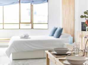 Un dormitorio moderno con cama, mesita de noche y ventana con cortinas.