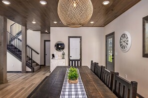 A dining area with a long wooden table, a central potted plant, and a black and white checkered runner.