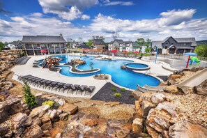 A large outdoor swimming pool with multiple sections, surrounded by lounge chairs and a playground area.