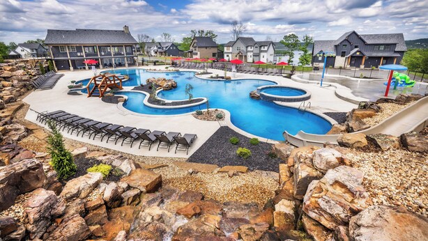 Une grande piscine extérieure dotée de plusieurs bassins et entourée d’un jardin de rochers.