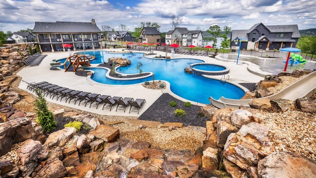 A large outdoor swimming pool with multiple sections and a rock garden surrounding it.