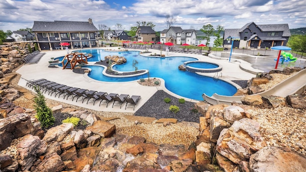 A large outdoor swimming pool with multiple sections and a rock garden surrounding it.