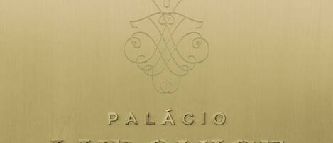 Texto en relieve sobre superficie metálica, con la inscripción 'PALÁCIO LUDOVICE WINE EXPERIENCE HOTEL LISBOA'.