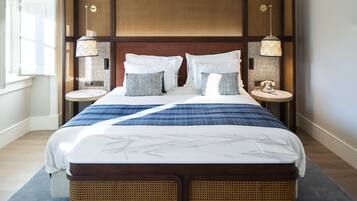 A large bed with a headboard, two bedside tables, and a wall-mounted clock.